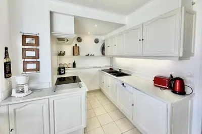 a white kitchen with white cabinets and a red appliance at Maison Les aloes - vue mer et proche centre ville in Propriano