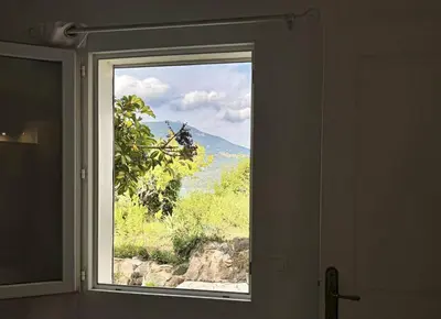 a window in a room with a view of a mountain at Maison Les aloes - vue mer et proche centre ville in Propriano