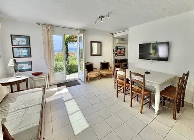 a living room with a white table and chairs at Maison Les aloes - vue mer et proche centre ville in Propriano