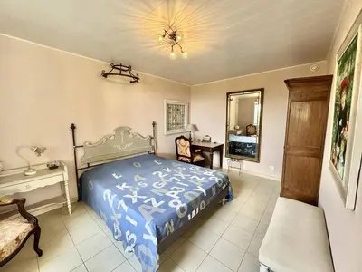 a bedroom with a bed and a table and a mirror at Maison Les aloes - vue mer et proche centre ville in Propriano