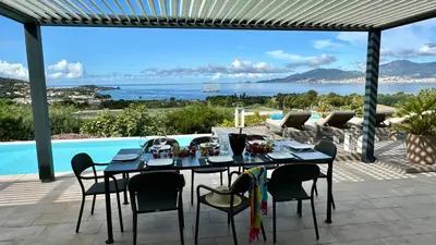 a dining table on a patio with a view of the ocean at Giulia, villa exceptionnelle, vue mer et Ajaccio in Porticcio