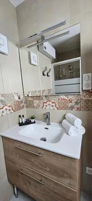 a bathroom with a white sink and a mirror at T3 Paradisiaque sur la plage, les pieds dans l'eau in Olmeto