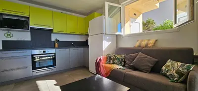 a living room with a couch and a kitchen at T3 Paradisiaque sur la plage, les pieds dans l'eau in Olmeto