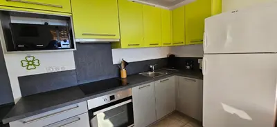a kitchen with yellow cabinets and a white refrigerator at T3 Paradisiaque sur la plage, les pieds dans l'eau in Olmeto