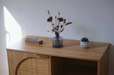 a wooden table with a vase of flowers on it at Charmant appartement climatisé proche mer in Linguizzetta