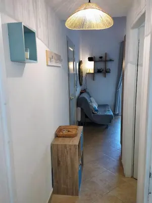 a hallway with a table and a room with a couch at Charmant appartement climatisé proche mer in Linguizzetta