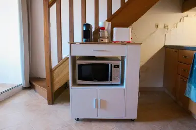 a microwave on a cart in a kitchen at Charmant appartement climatisé proche mer in Linguizzetta