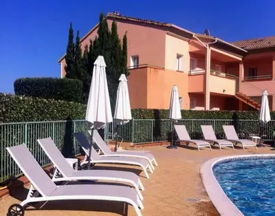 a row of lounge chairs with umbrellas next to a pool at Charmant appartement climatisé proche mer in Linguizzetta
