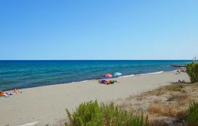 a beach with people laying on the sand and the ocean at Beautiful Home In Cervione With Wifi in Cervione