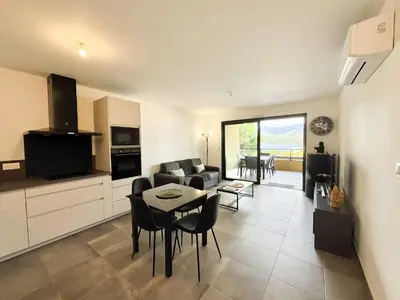 a kitchen and living room with a table and chairs at T2 moderne avec vue mer et proche centre-ville in Propriano