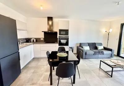 a kitchen and living room with a table and a couch at T2 moderne avec vue mer et proche centre-ville in Propriano