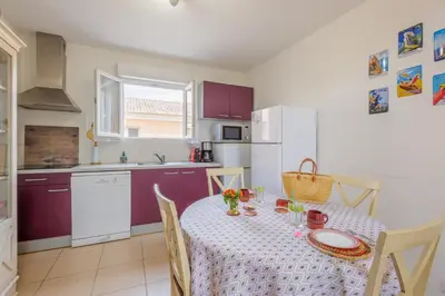 a kitchen with a table with a white table cloth at Jaso - Maison à 5min de la plage in Cervione