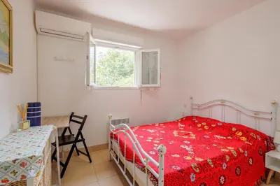 a bedroom with a bed and a table and a window at Jaso - Maison à 5min de la plage in Cervione