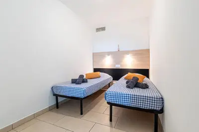 two twin beds in a room with white walls at La Marina - Appt climatisé pour 4 in Sari Solenzara