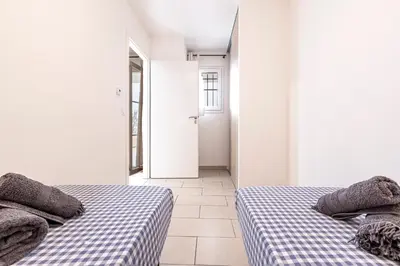 two beds in a white room with a hallway at La Marina - Appt climatisé pour 4 in Sari Solenzara