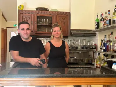 a man and a woman standing behind a counter in a kitchen at Gîte de randonneurs Bocca bè in Chisa