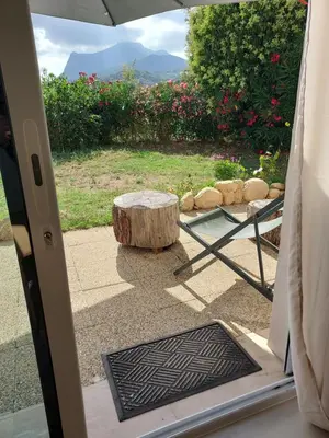 an open door to a patio with a table and a stump at Suite indépendante avec vue in Sarrola-Carcopino