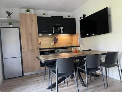 a kitchen with a table with chairs and a microwave at Mini Villa T4 duplex dans résidence hôtelière Fiori di Cala Rossa superbement arborée rénovée en 2023 - chez Anne avec piscine chauffée in Lecci