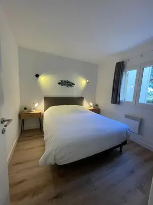 a bedroom with a white bed and two windows at Mini Villa T4 duplex dans résidence hôtelière Fiori di Cala Rossa superbement arborée rénovée en 2023 - chez Anne avec piscine chauffée in Lecci