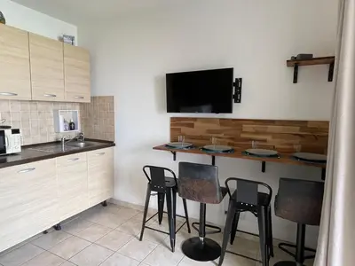a kitchen with a bar with stools and a tv at Carpediem-corsica Bravone in Linguizzetta