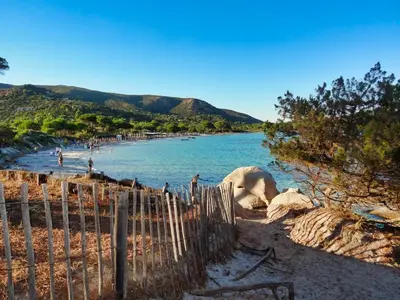 a beach with a fence and people in the water at U Sole Livante mini villa vue mer Santa Giulia in Porto-Vecchio