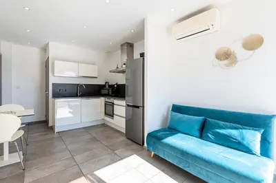 a living room with a blue couch and a kitchen at Paradisu - Apt climatisé de 32 m² in Porticcio