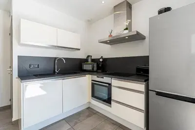 a kitchen with white cabinets and a stainless steel refrigerator at Paradisu - Apt climatisé de 32 m² in Porticcio