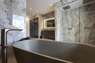 a bath tub in a bathroom with a stone wall at Tigliola Resort in Porto-Vecchio