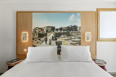 a bedroom with a white bed with a painting on the wall at Novaya Suites in Ajaccio