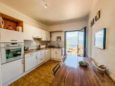 a kitchen with white cabinets and a table and a window at Joli T3 moderne avec vue imprenable sur la mer in Propriano