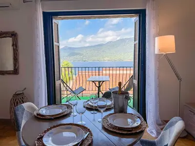 a dining room with a table and a large window at Joli T3 moderne avec vue imprenable sur la mer in Propriano