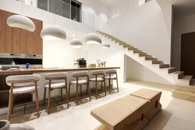 a kitchen with a bar with stools and a staircase at Villa Tigliola in Porto-Vecchio