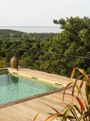 a swimming pool with a fence and a wooden deck at Résidence & Villas Oradoro - Proche Île Rousse in Belgodère