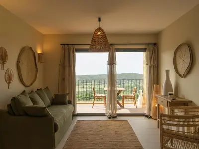 a living room with a couch and a large sliding glass door at Résidence & Villas Oradoro - Proche Île Rousse in Belgodère