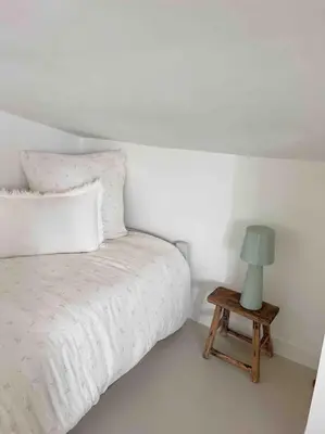 a white bedroom with a bed and a lamp on a table at LA GRANDE JANE petite villa bord de mer in Borgo