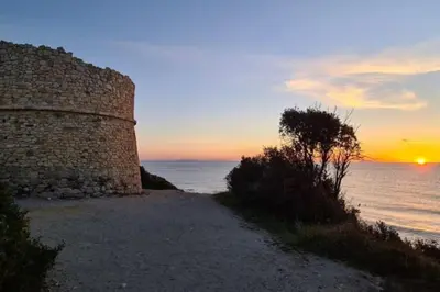 a stone wall next to the ocean at sunset at T2 Mare - Casa Mattea in Aléria