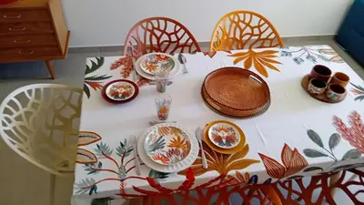 a table with plates and bowls on top of it at T2 neuf situation Topissime village de Cargèse Vue mer Toutes commodités in Cargèse