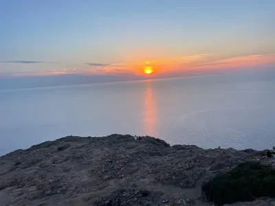 a sunset over the water with people standing on a hill at T2 neuf situation Topissime village de Cargèse Vue mer Toutes commodités in Cargèse