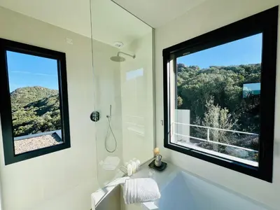 a bathroom with a tub and a large window at A Vista - Villa luxe, piscine, vue mer panoramique - Classée 4 étoiles in Figari