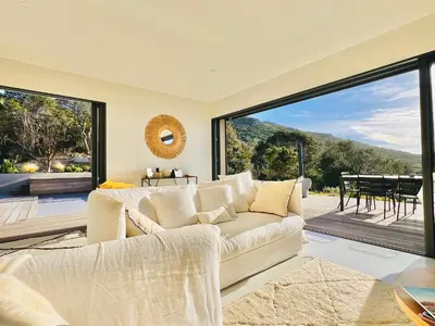 a living room with a couch and a large window at A Vista - Villa luxe, piscine, vue mer panoramique - Classée 4 étoiles in Figari