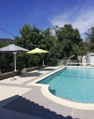 a large swimming pool with an umbrella and an umbrella at Location Estivale en Haute Corse in Scata