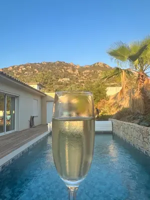 a glass of water sitting next to a swimming pool at Villa élégante piscine privée Palombaggia Porto-vecchio in Porto-Vecchio