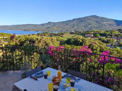 a table with food and drinks on a balcony with flowers at Villa KALLISTE 3 pièces avec vue mer sur les hauteurs de Propriano in Propriano