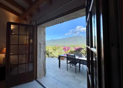 an open door to a patio with a table and a view at Villa KALLISTE 3 pièces avec vue mer sur les hauteurs de Propriano in Propriano