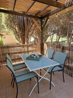 a table and chairs on a patio under a pergola at Mini villa 70 - piscine chauffée in Serra-di-Ferro