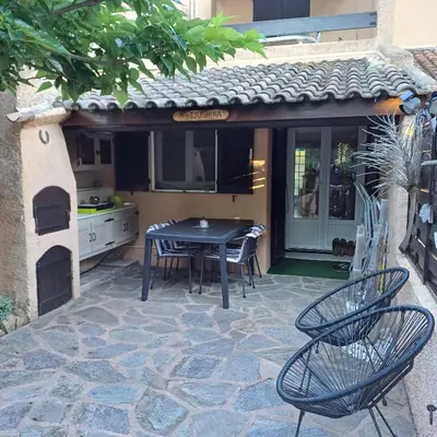 a patio with a table and chairs and a kitchen at A-Tjughina in San Ciprianu