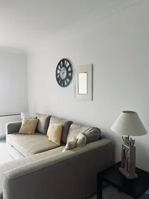 a living room with a couch and a clock on the wall at T2 vue mer à 8 min du centre ville d'Ajaccio et 1 min des plages in Ajaccio