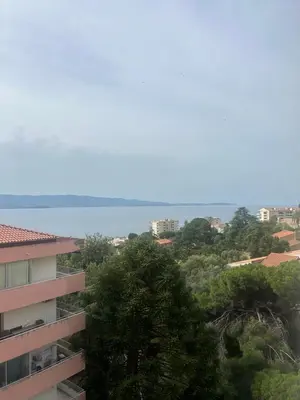a view of a building with trees and the ocean at T2 vue mer à 8 min du centre ville d'Ajaccio et 1 min des plages in Ajaccio