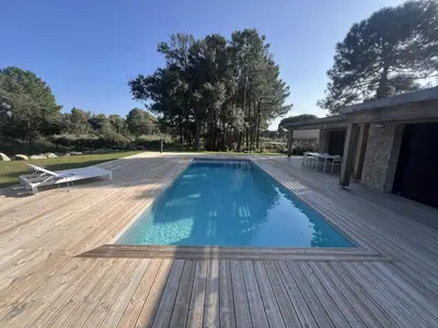 a large swimming pool on a wooden deck at Les Villas de Fiori Di Cala Rossa in Lecci