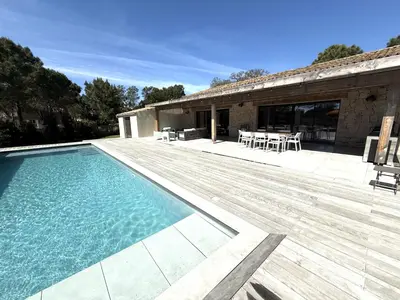 a house with a swimming pool and a wooden deck at Les Villas de Fiori Di Cala Rossa in Lecci